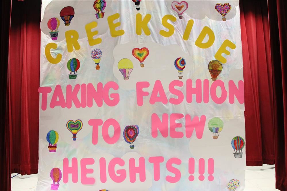  Picture of the background on stage. It reads: Creekside Taking Fashion to New Heights.